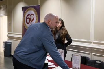 Guest at Table Looking at Program Schedules for AI Day in the Capital Event